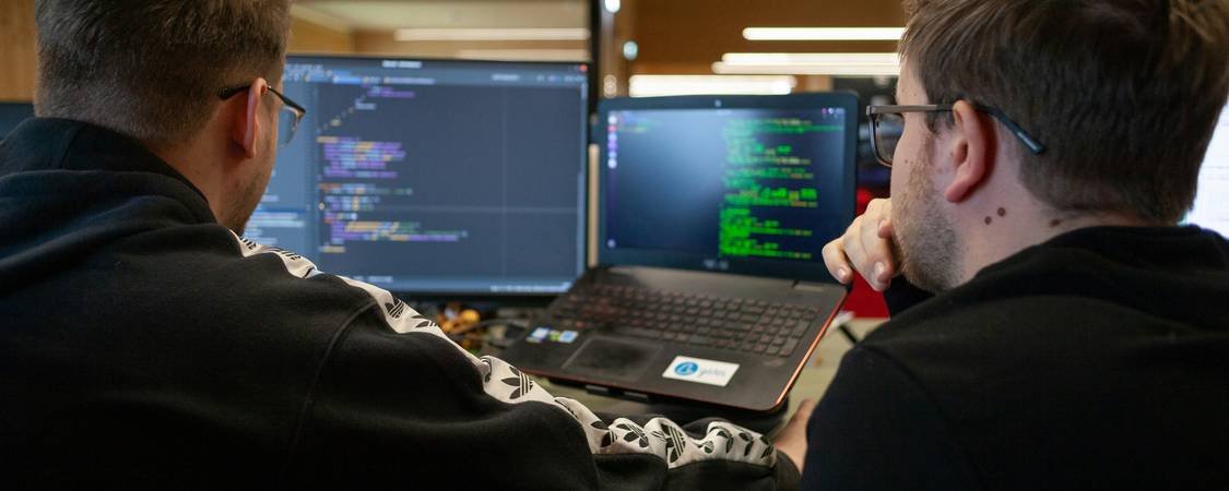 A photo of developers coding automation bots in a modern workspace, with server racks in the background, illustrating the concept of bots using proxies